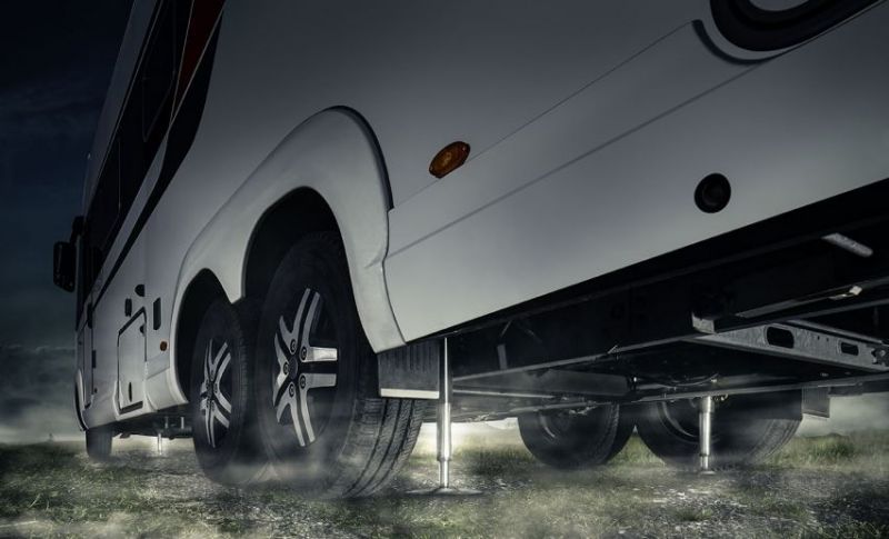 Ein weißes Wohnmobil steht auf Stelzen auf einem Feld.