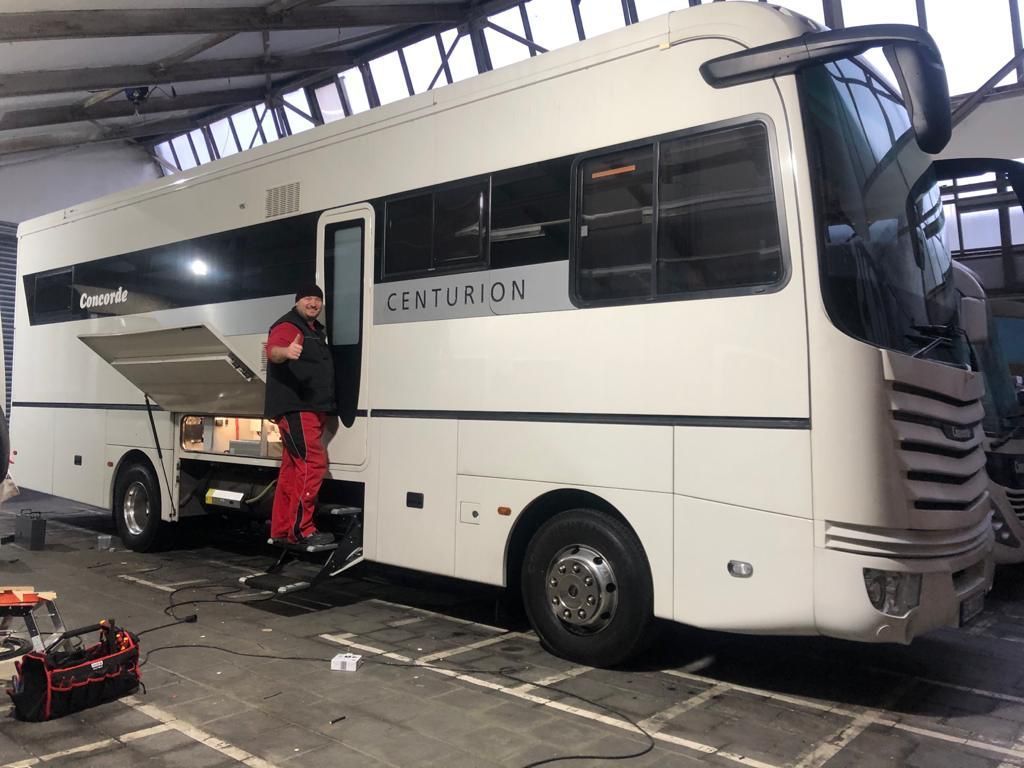 Ein Mann steht neben einem großen weißen Bus in einer Garage.