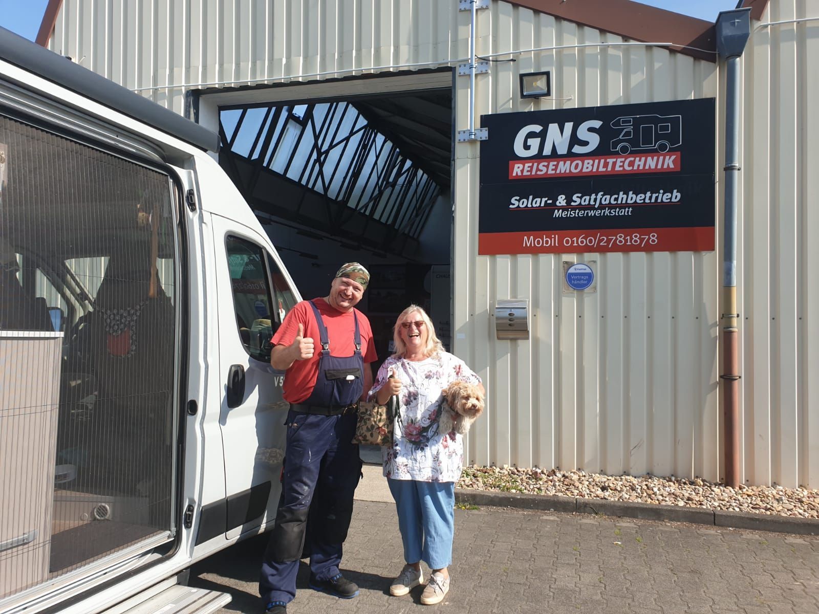 Ein Mann und eine Frau stehen vor einem Lieferwagen und zeigen den Daumen nach oben.