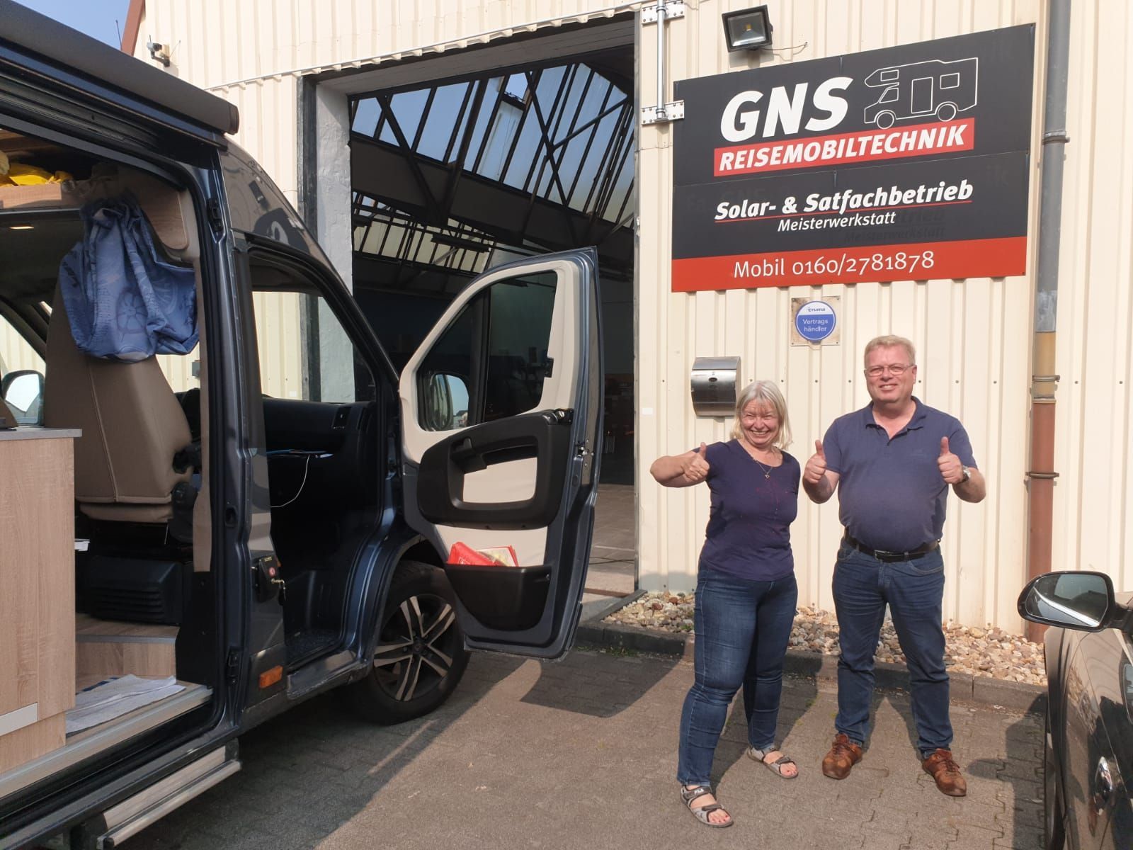 Ein Mann und eine Frau stehen vor einem Lieferwagen.