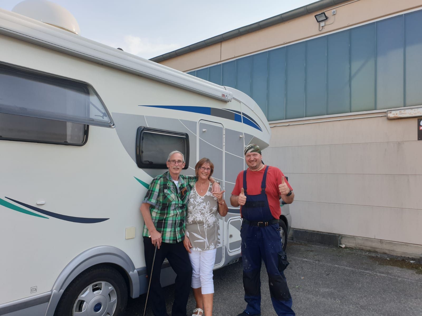 Drei Leute stehen vor einem Wohnmobil und zeigen den Daumen nach oben