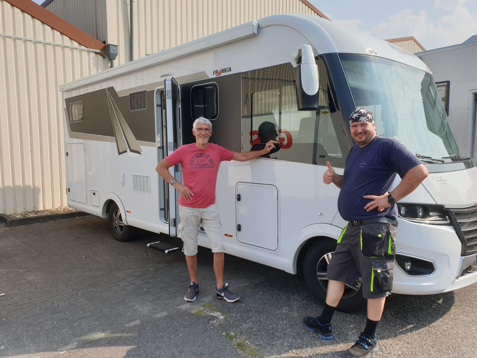 Zwei Männer stehen vor einem großen weißen Wohnmobil.