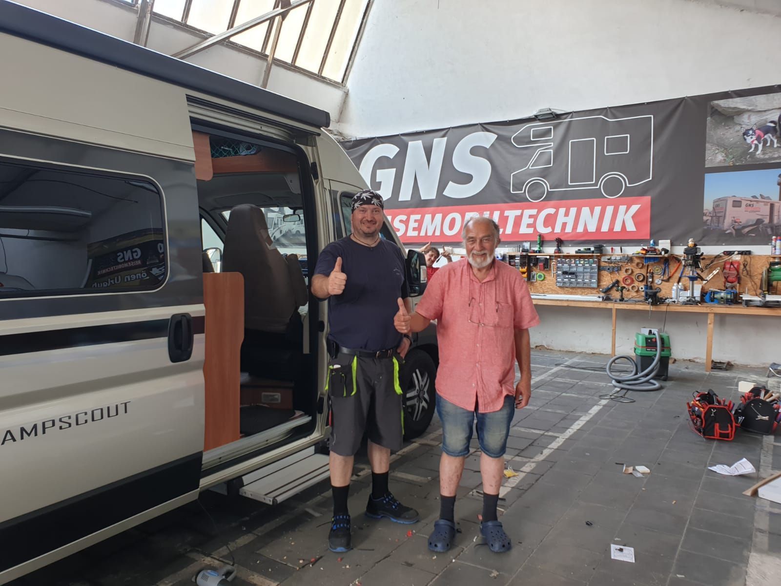 Zwei Männer stehen vor einem Lieferwagen in einer Garage.