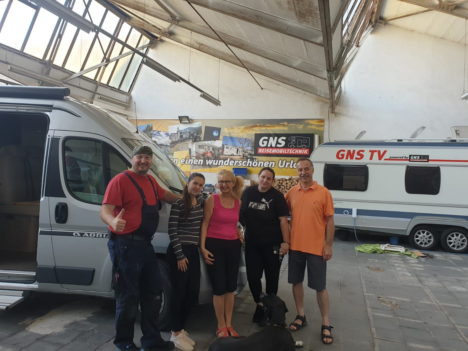 Eine Gruppe von Menschen steht vor einem Lieferwagen mit der Aufschrift „GNS TV“