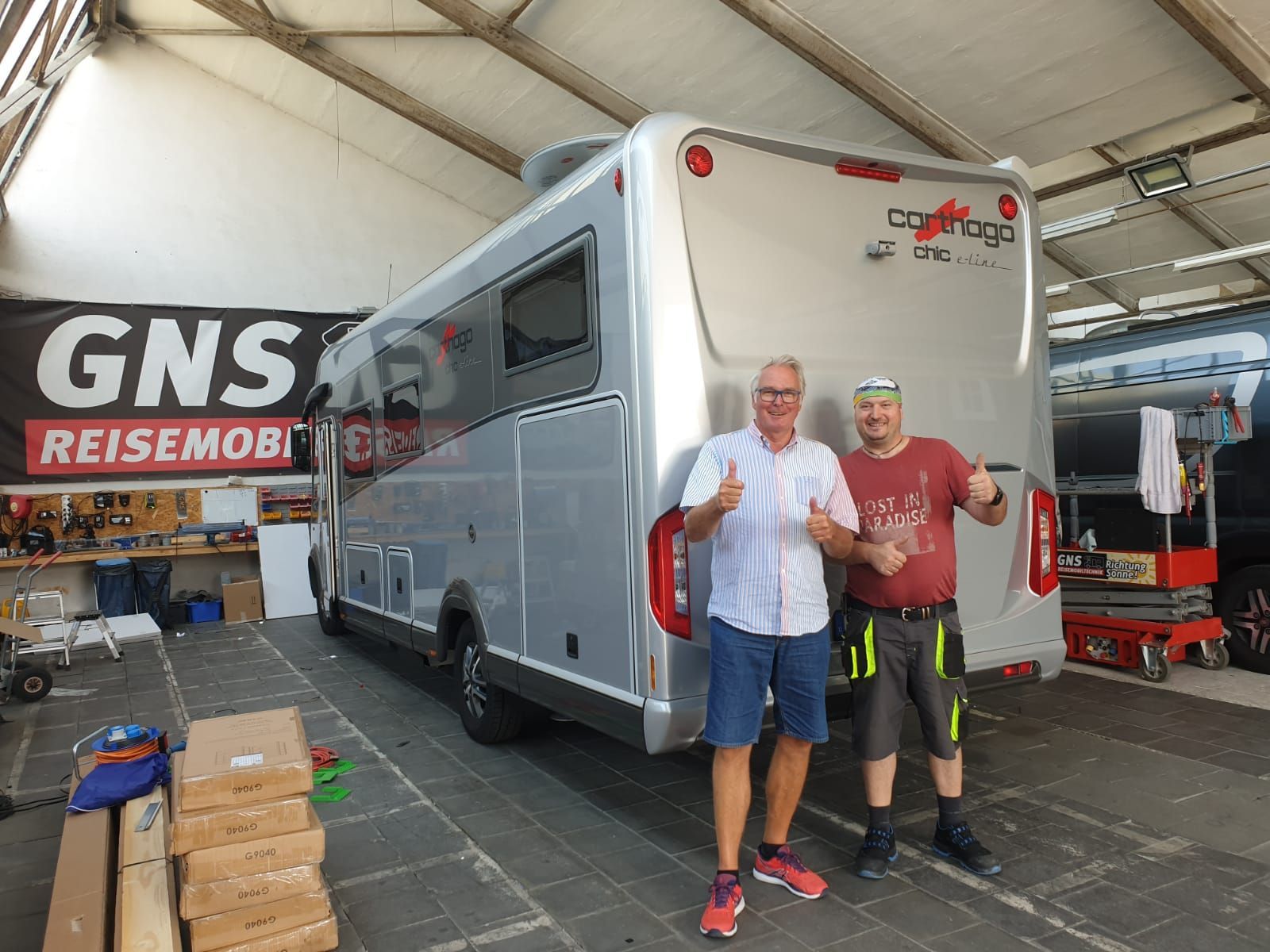 Zwei Männer stehen vor einem Wohnmobil in einer Garage.