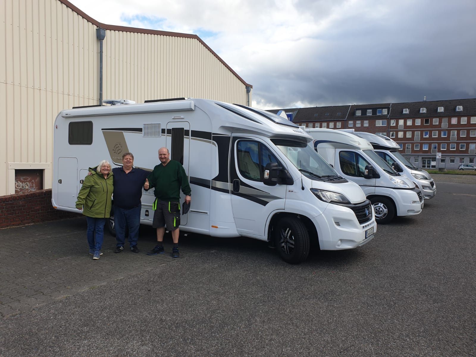 Eine Gruppe von Menschen steht vor einer Reihe von Wohnmobilen.