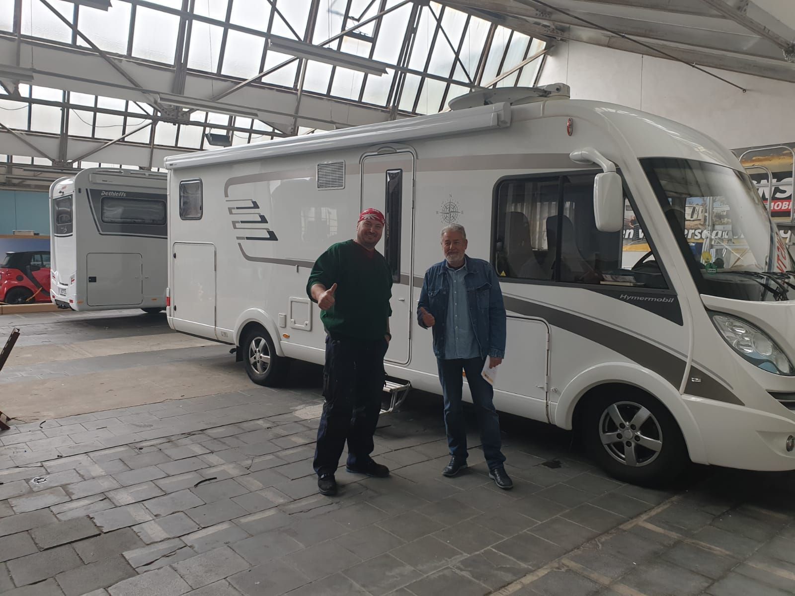 Zwei Männer stehen vor einem Wohnmobil in einer Garage.