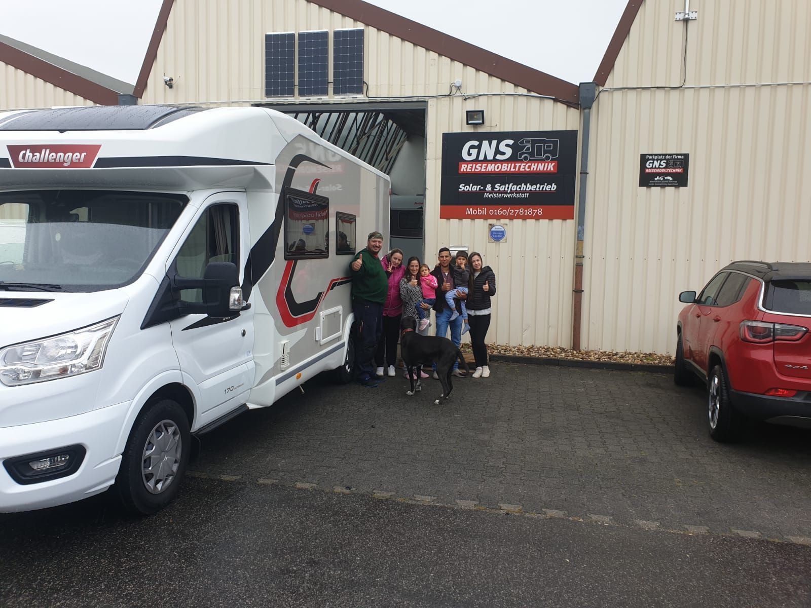 Eine Gruppe von Menschen steht vor einem Wohnmobil.