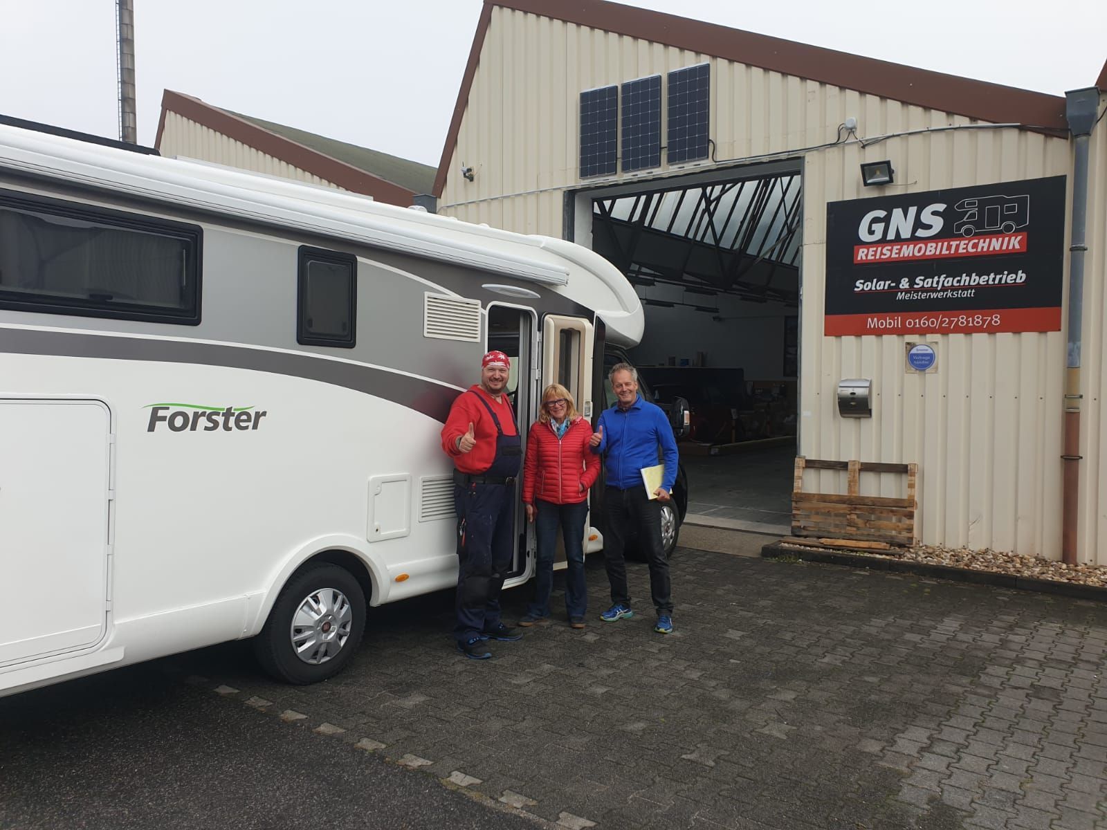 Eine Gruppe von Leuten steht vor einem Wohnmobil.