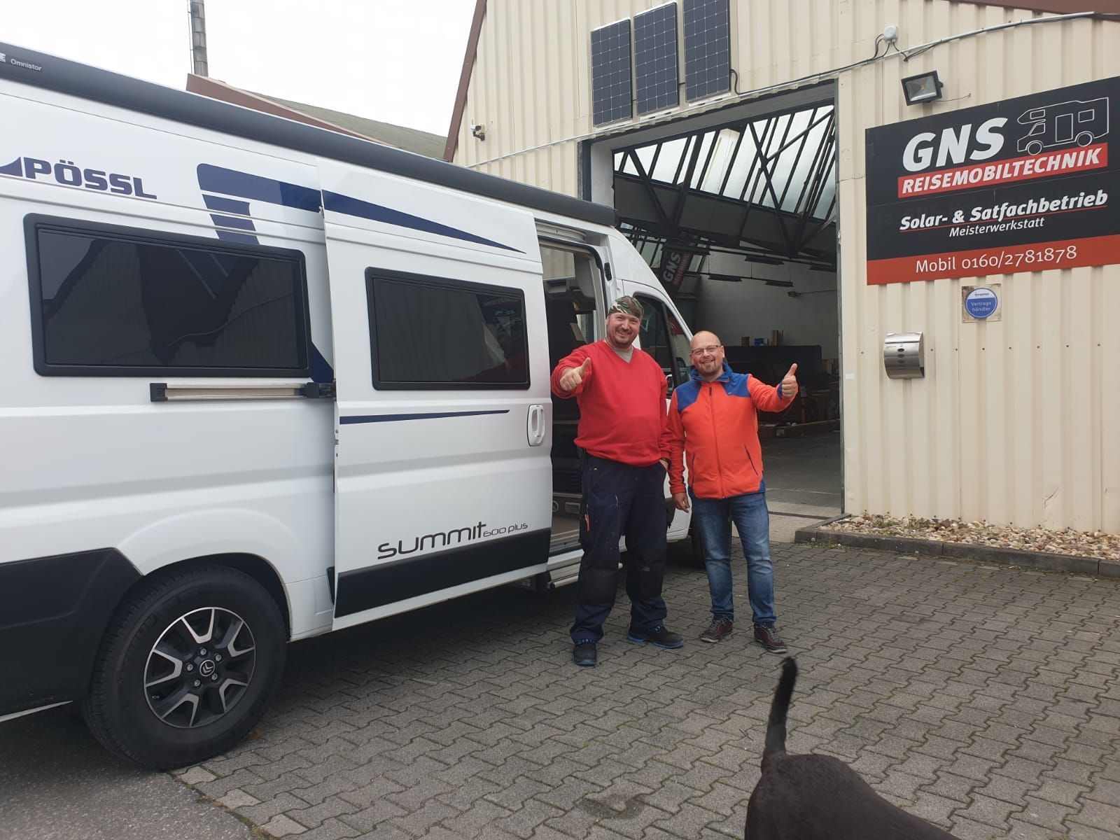 Zwei Männer stehen vor einem Wohnmobil und strecken den Daumen nach oben.