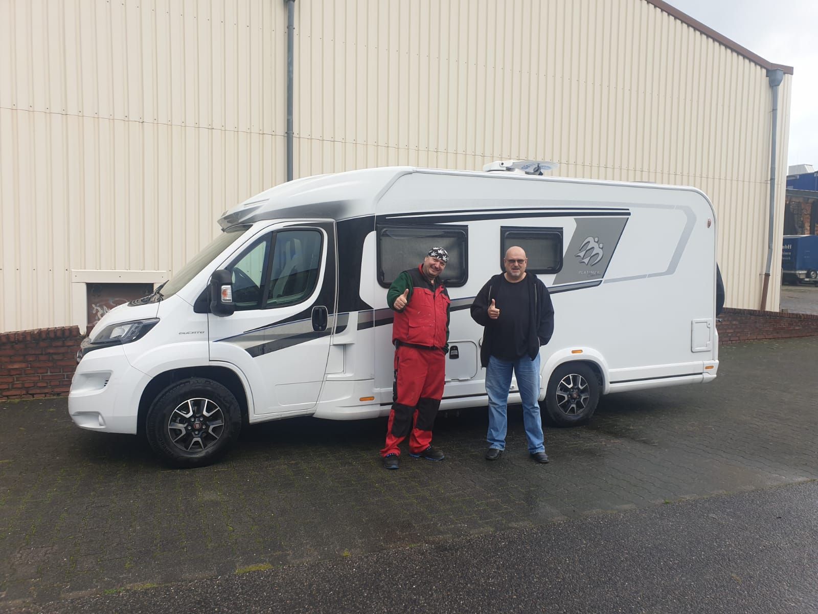 Zwei Männer stehen vor einem Wohnmobil.