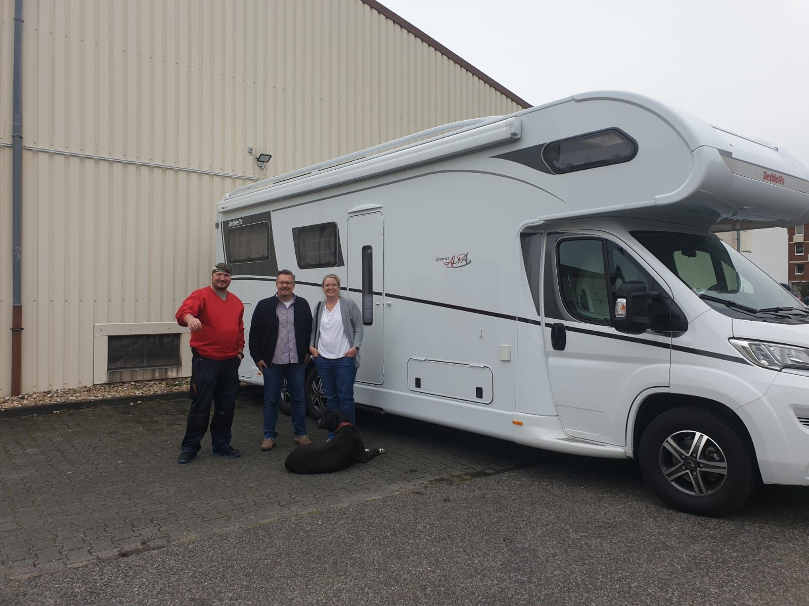 Drei Personen stehen vor einem weißen Wohnmobil.