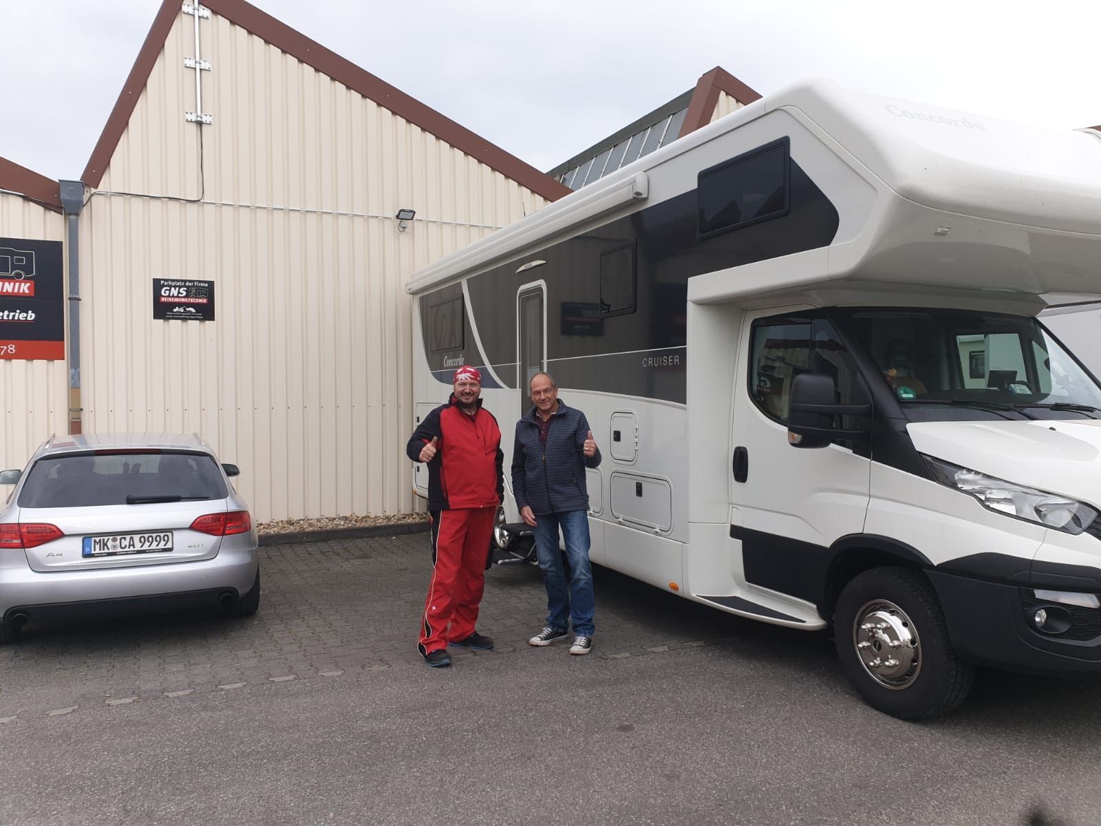 Zwei Männer stehen vor einem großen weißen Wohnmobil