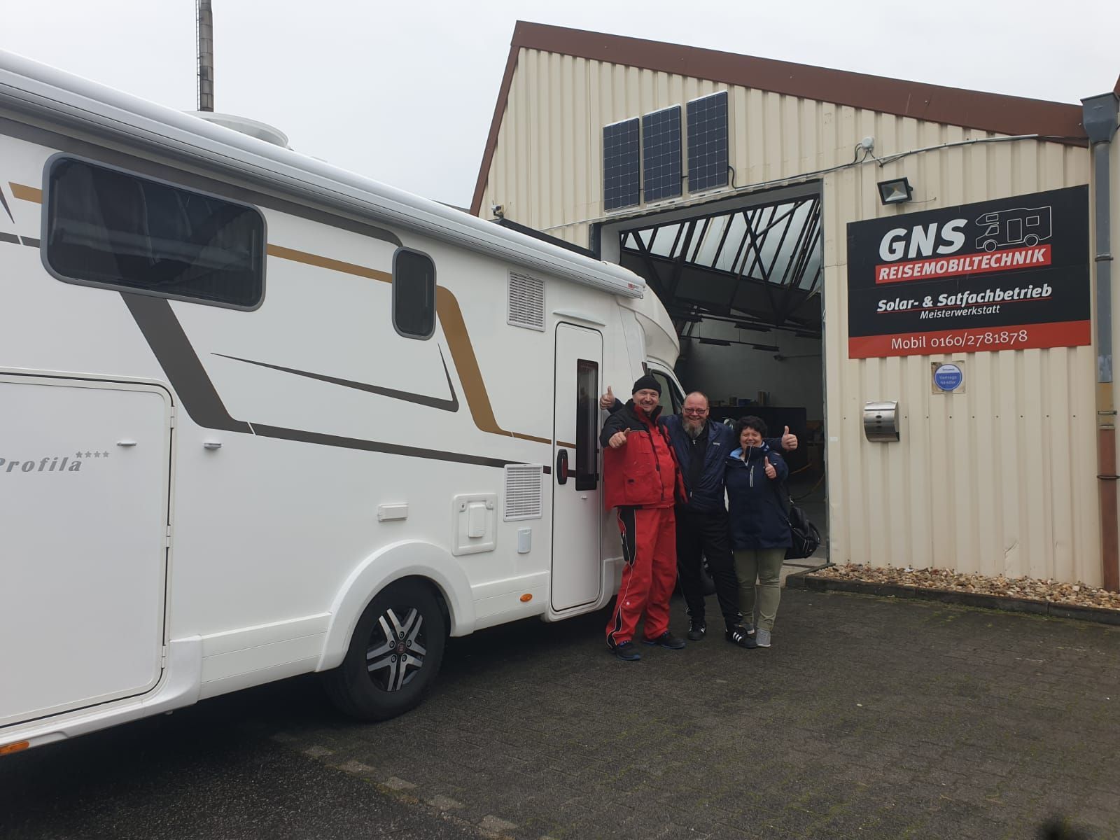 Eine Gruppe von Leuten steht vor einem Wohnmobil.