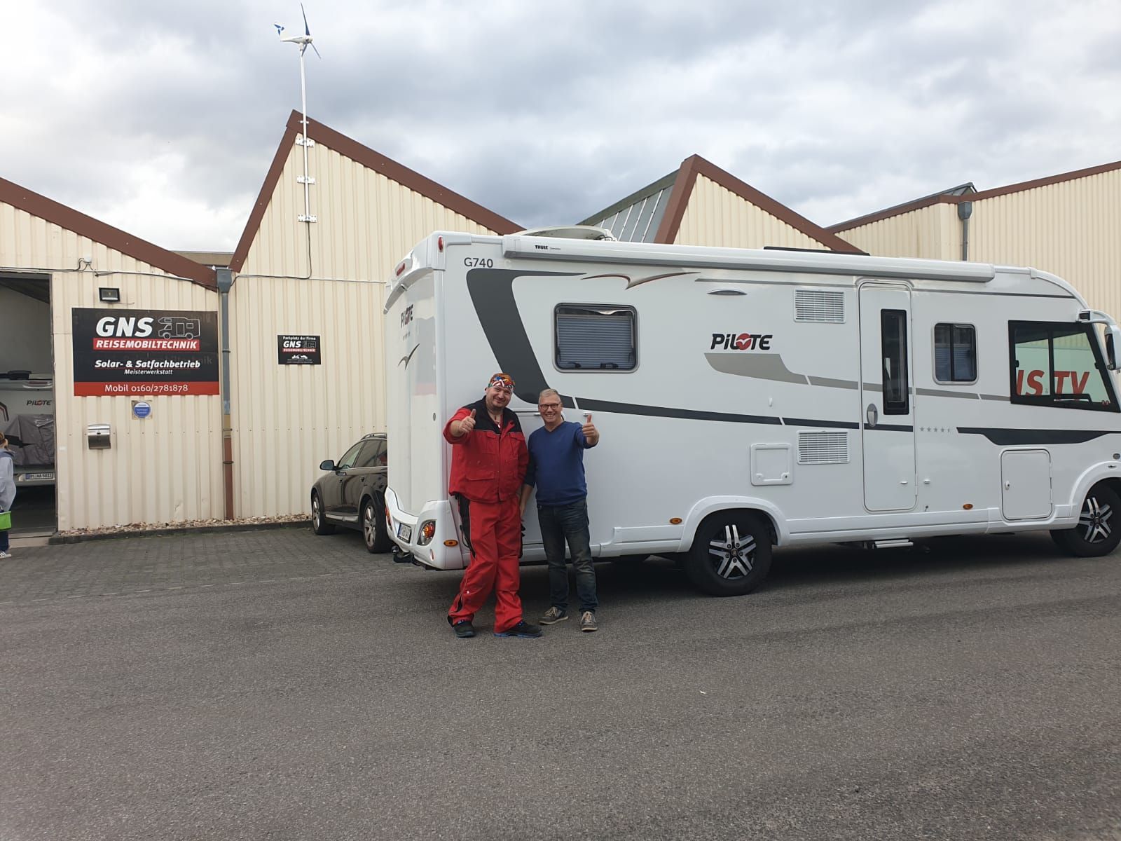 Zwei Männer stehen auf einem Parkplatz vor einem Wohnmobil.