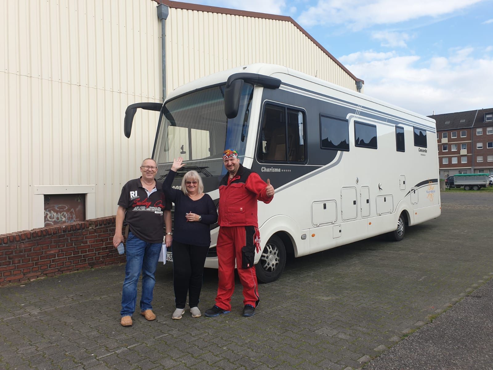 Drei Personen stehen vor einem großen weißen Bus.