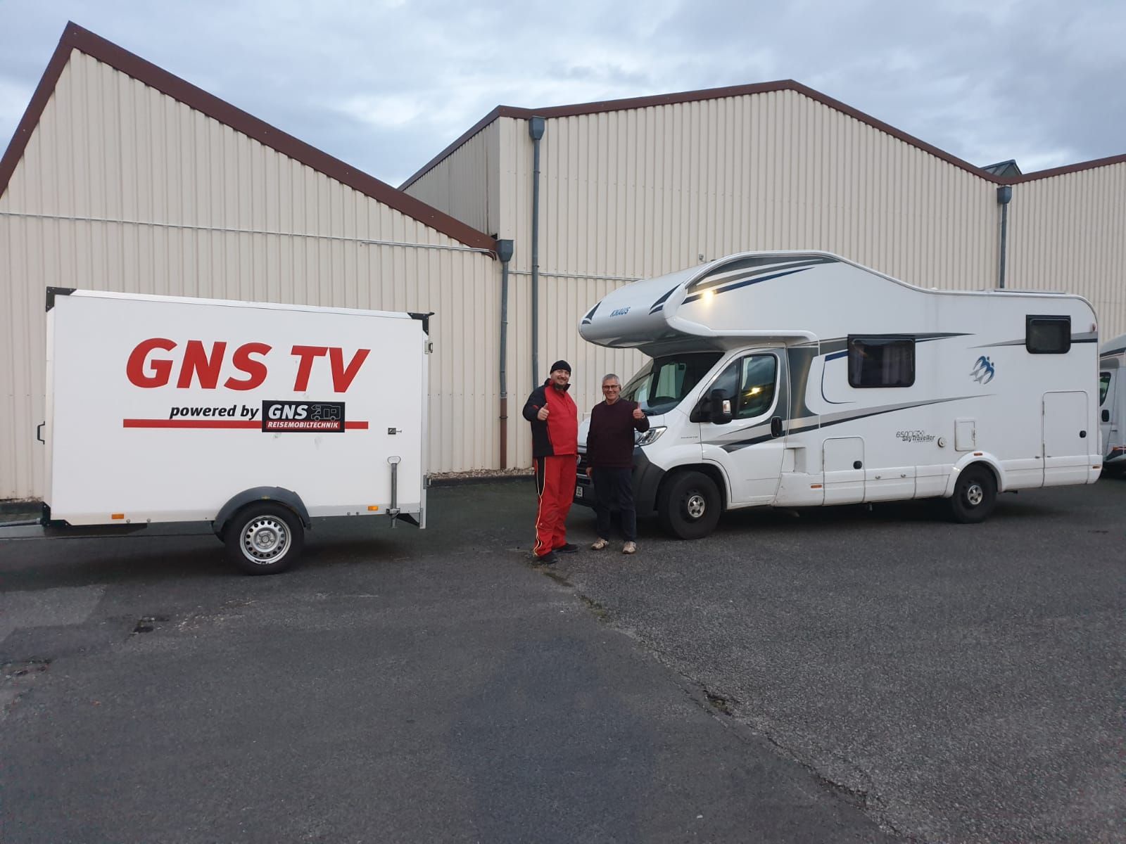 Zwei Männer stehen neben einem Anhänger mit der Aufschrift „GNS TV“