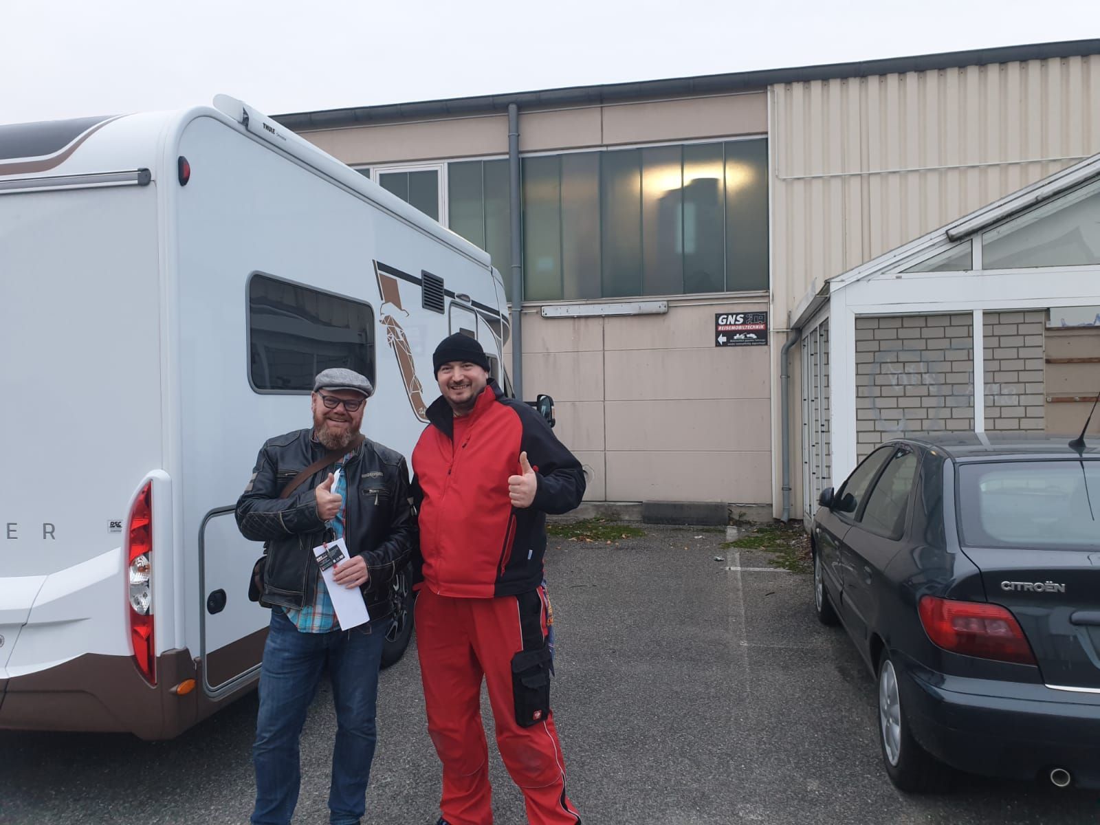 Zwei Männer stehen vor einem Wohnmobil und einem Auto