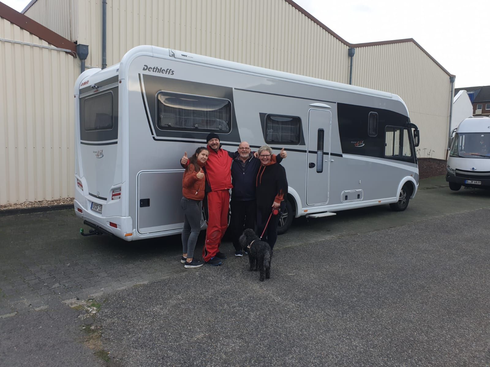 Eine Gruppe von Menschen steht vor einem großen Wohnmobil.