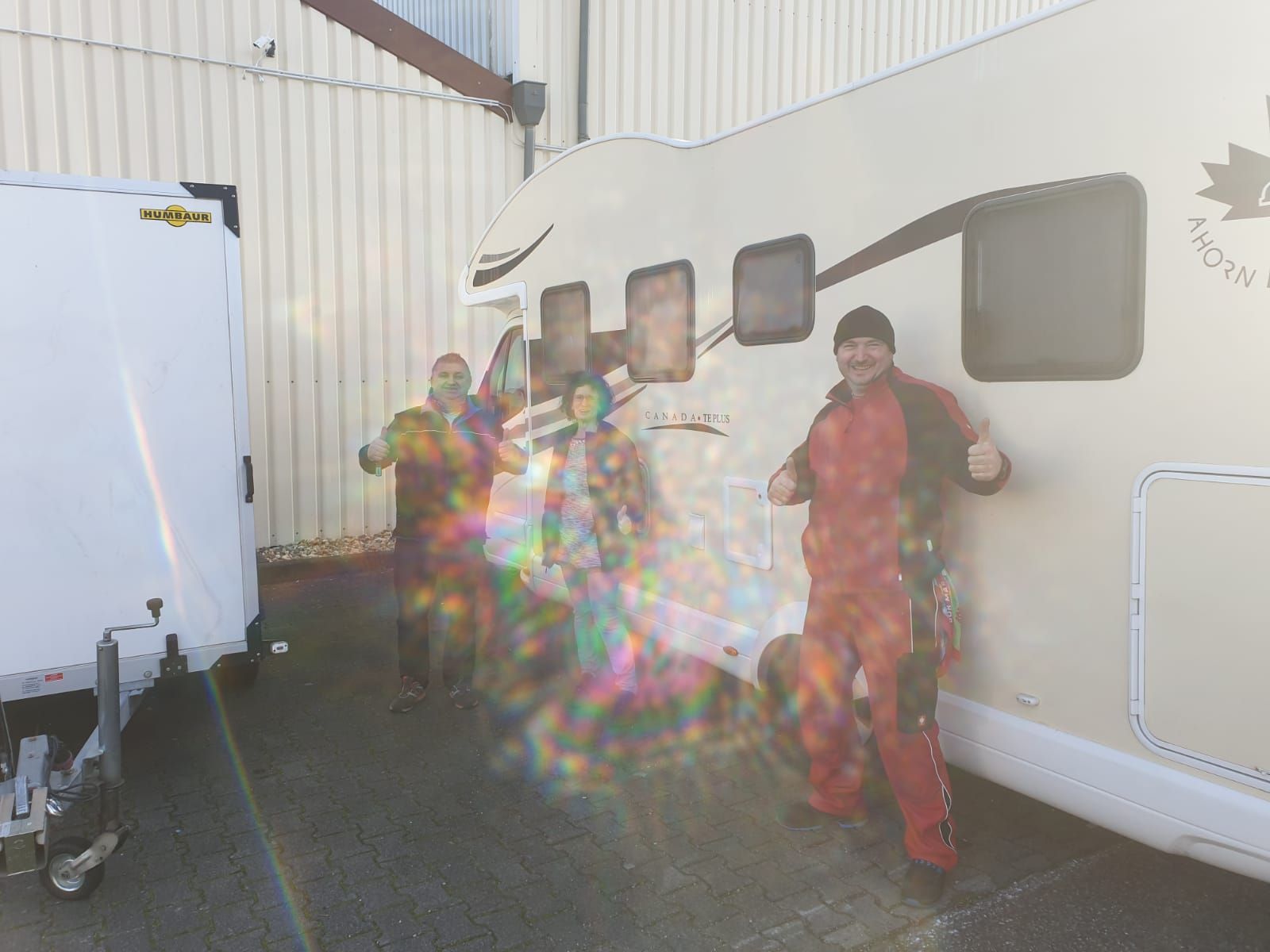 Eine Gruppe von Leuten steht vor einem Wohnmobil.