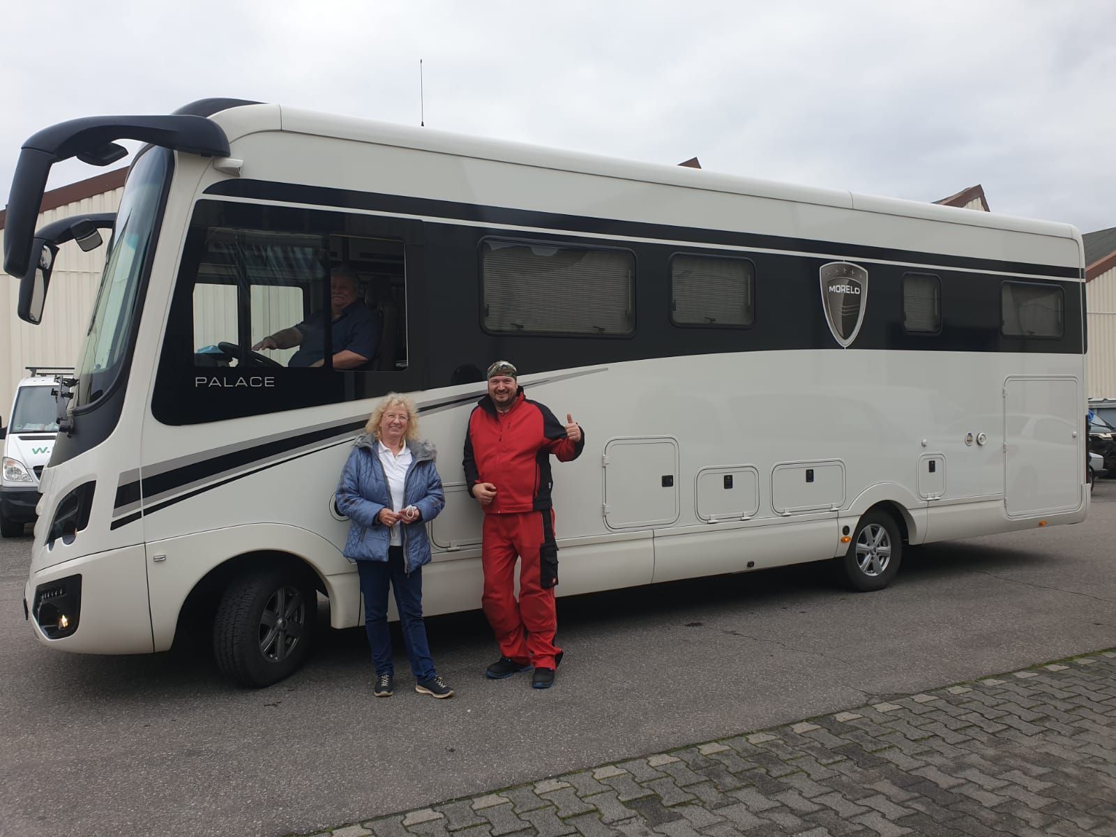 Zwei Personen stehen vor einem großen weißen Wohnmobil.