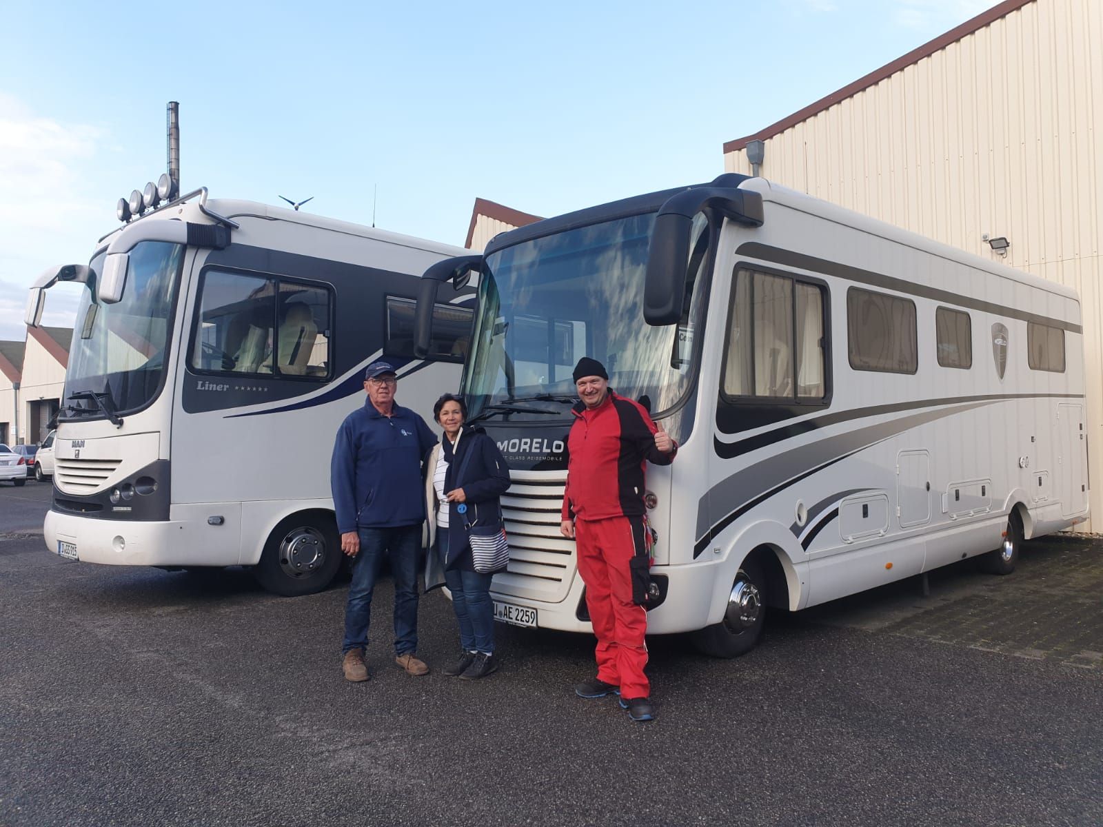 Eine gruppe von leuten steht vor zwei wohnmobilen.