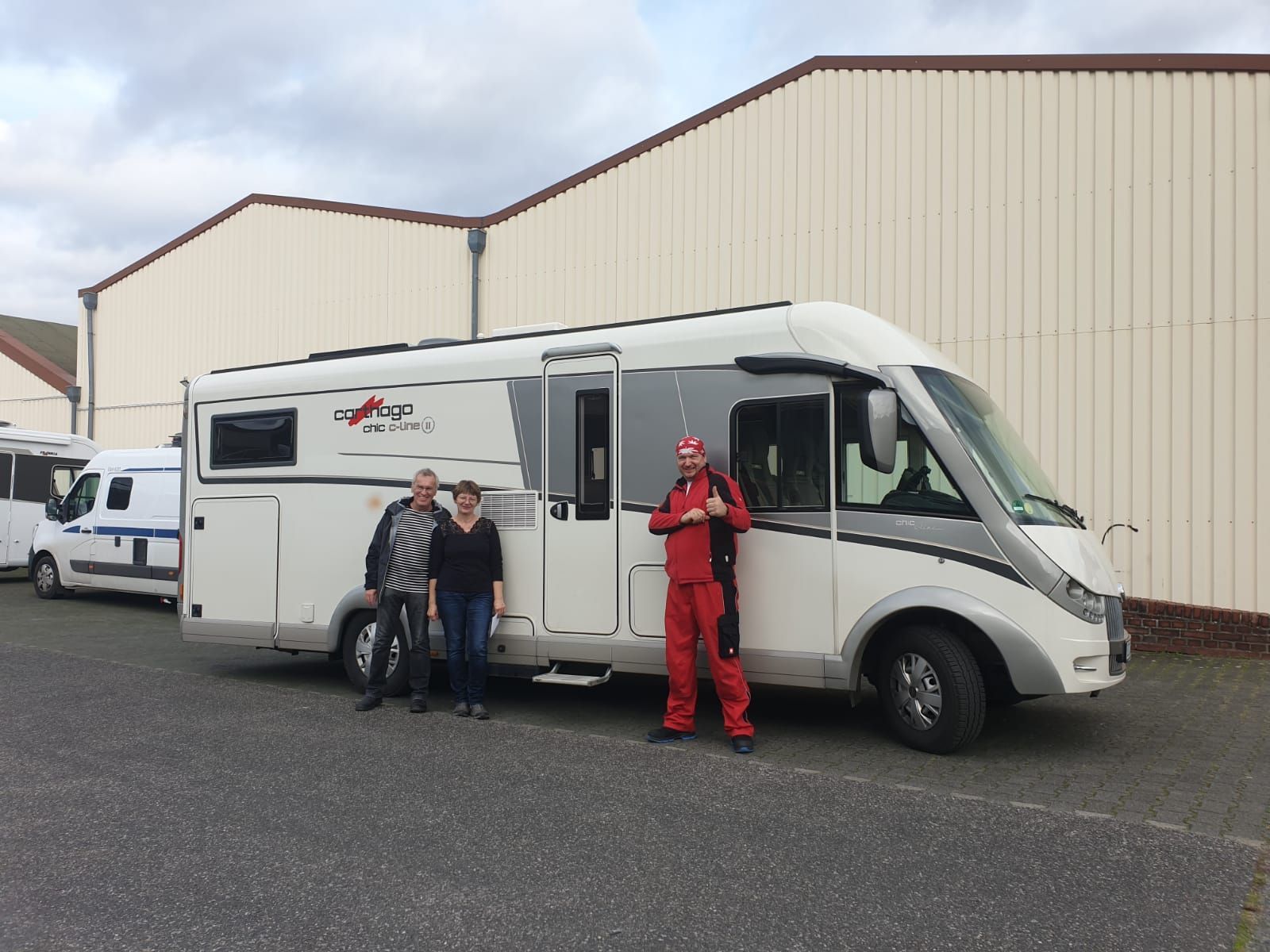 Eine Gruppe von Menschen steht vor einem weißen Wohnmobil.