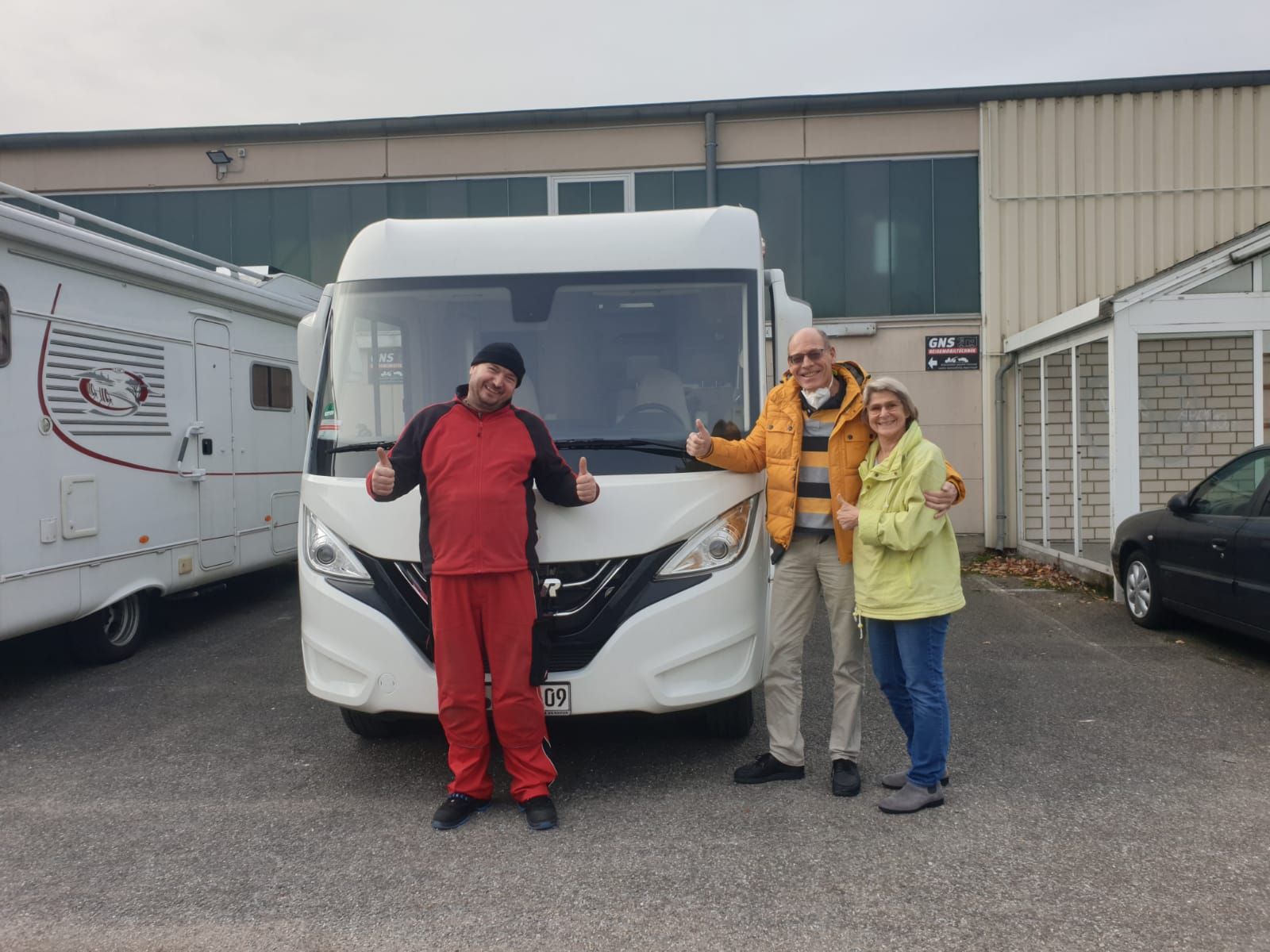 Eine Gruppe von Menschen steht vor einem Wohnmobil.
