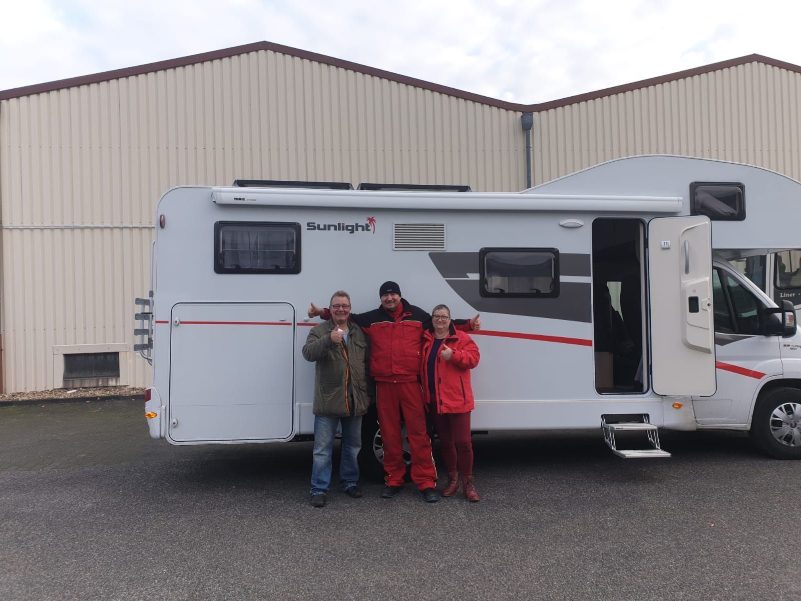 Eine Gruppe von Menschen posiert vor einem Wohnmobil für ein Foto.