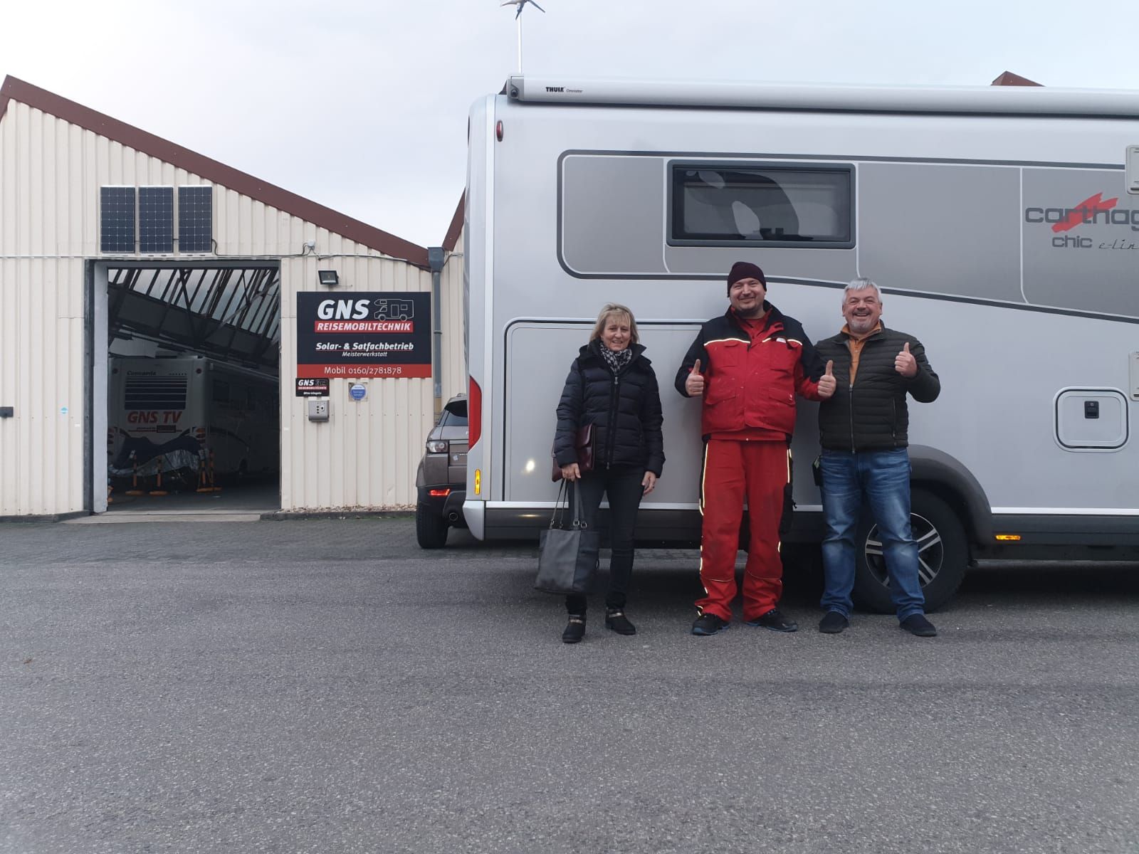 Eine Gruppe von Menschen steht vor einem Wohnmobil