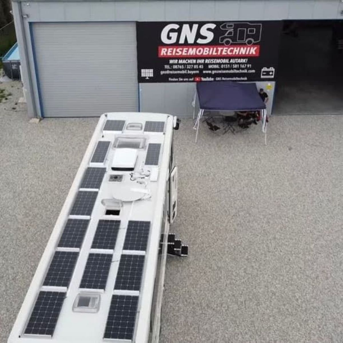 Eine Luftaufnahme eines Wohnmobils mit Solarmodulen und einem Schild mit der Aufschrift „GNS Reisemobiltechnik“