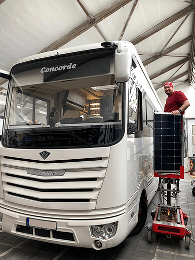 Ein Mann steht neben einem Wohnmobil in einer Garage.