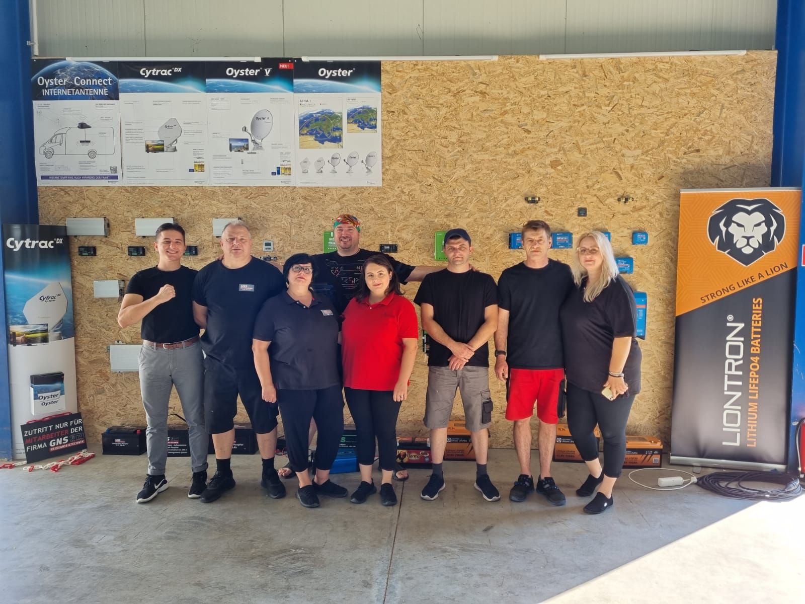 Eine Gruppe von Menschen posiert für ein Foto vor einem Liontron-Schild