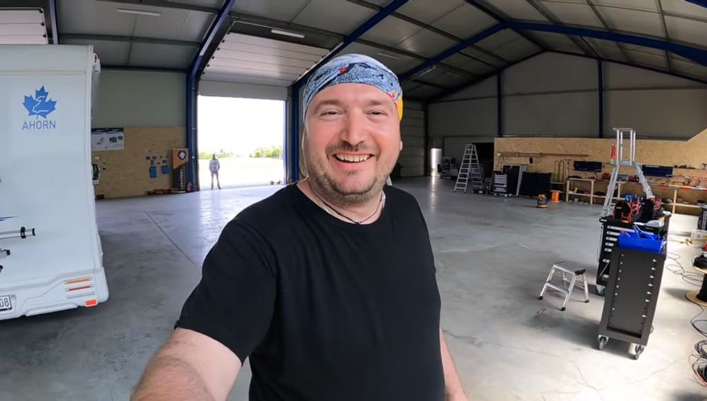 Ein Mann mit einem Kopftuch steht in einer Lagerhalle.