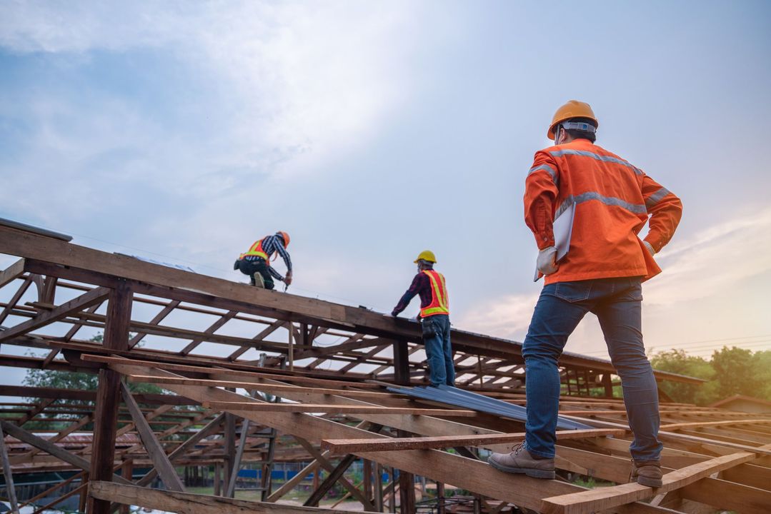Un grupo de trabajadores de la construcción está trabajando en un techo en un sitio de construcción.