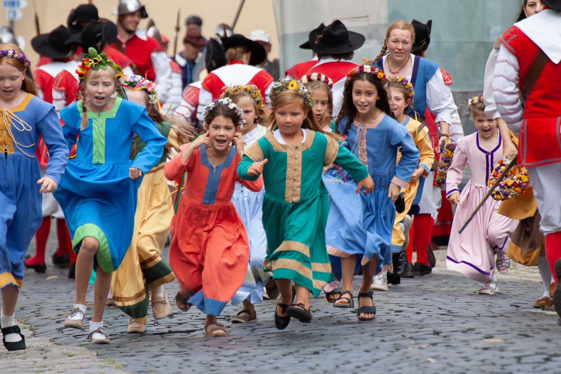 Laufende Kinder in bunten historischen Kleidern und mit Blumen im Haar