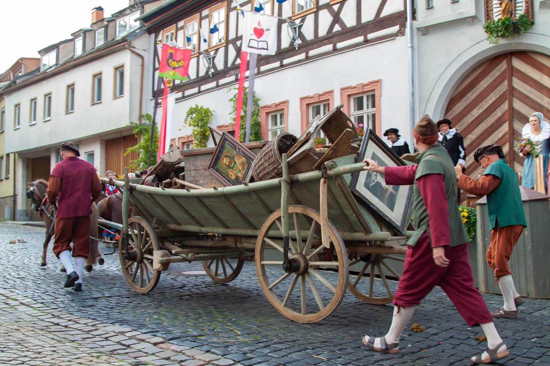 Szene aus dem Heimatspiel mit mehreren Personen die einen Holzwagen schieben
