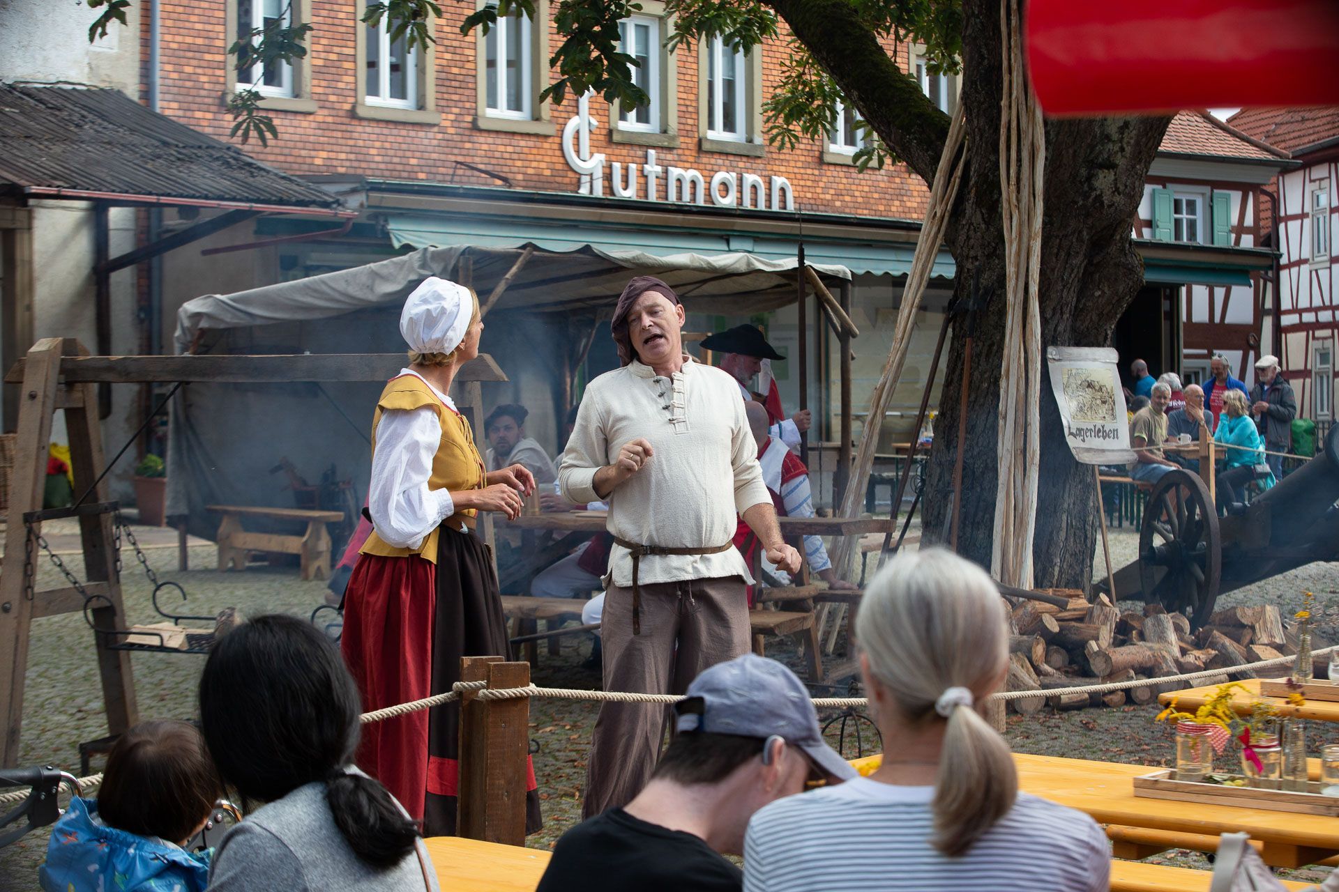 Ein Paar in historischer Kleidung im Gespräch vor einer Gruppe Zuschauer