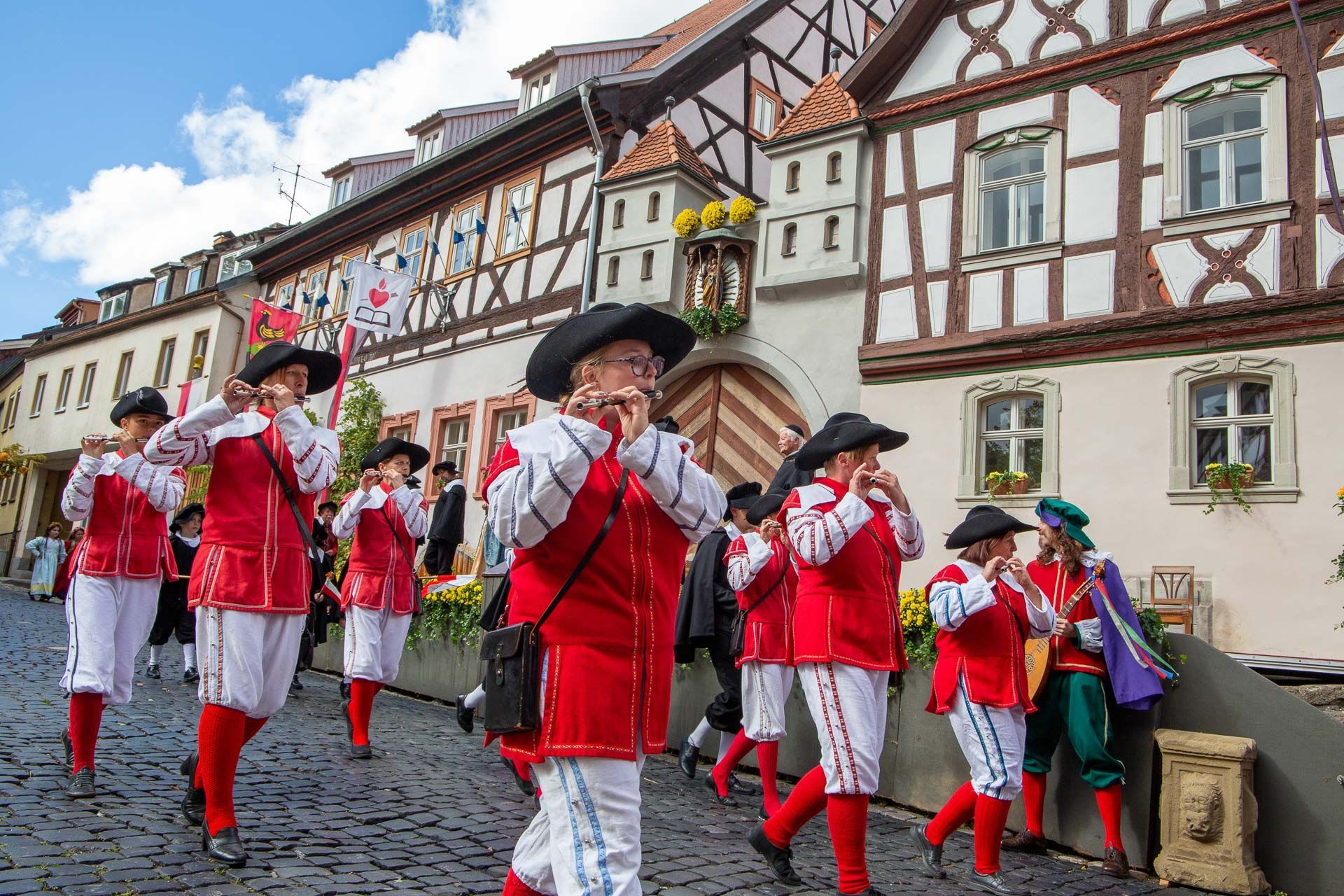 Szene aus dem Heimatspiel mit einer Gruppe Musikanten in rot-weißen Kostümen