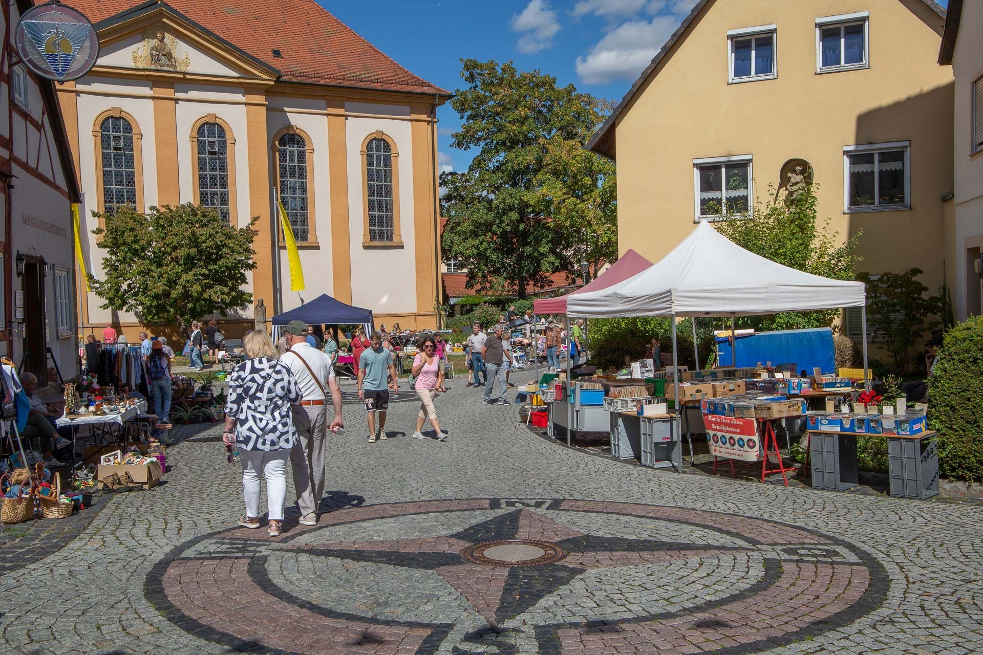 Flohmarkt mit verschiedenen Marktständen rund um eine Kirche