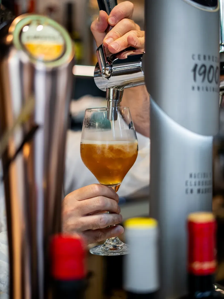 Servirse cerveza de un grifo en una copa con tallo en un bar.