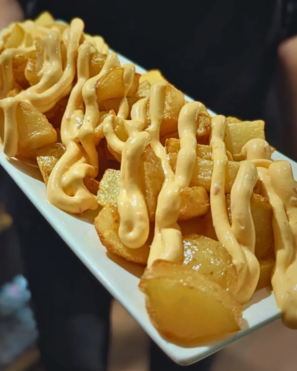 Plato blanco de pasteles dorados rociados con salsa cremosa, servido en un restaurante.