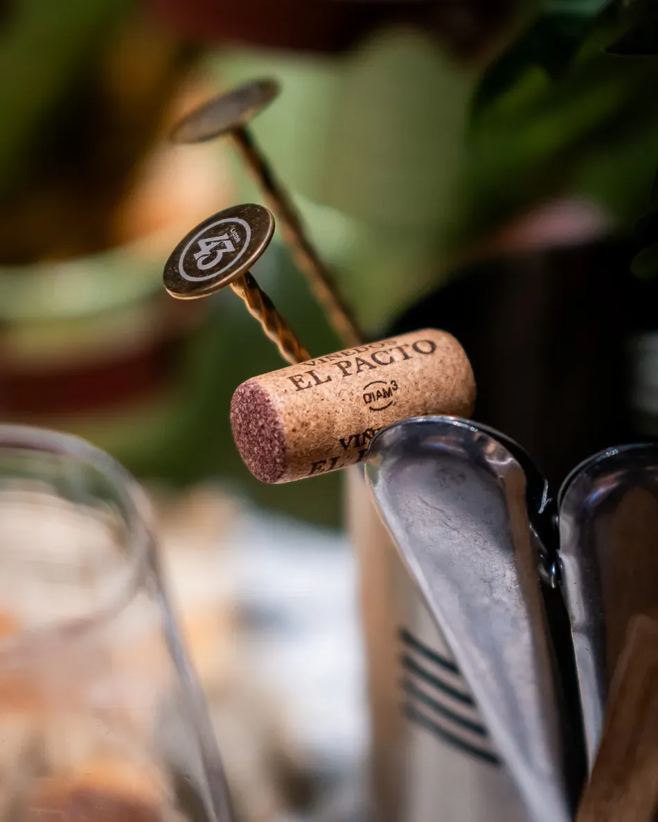 Corcho de vino con un palillo de cóctel de metal en un vaso, fondo borroso de un bar