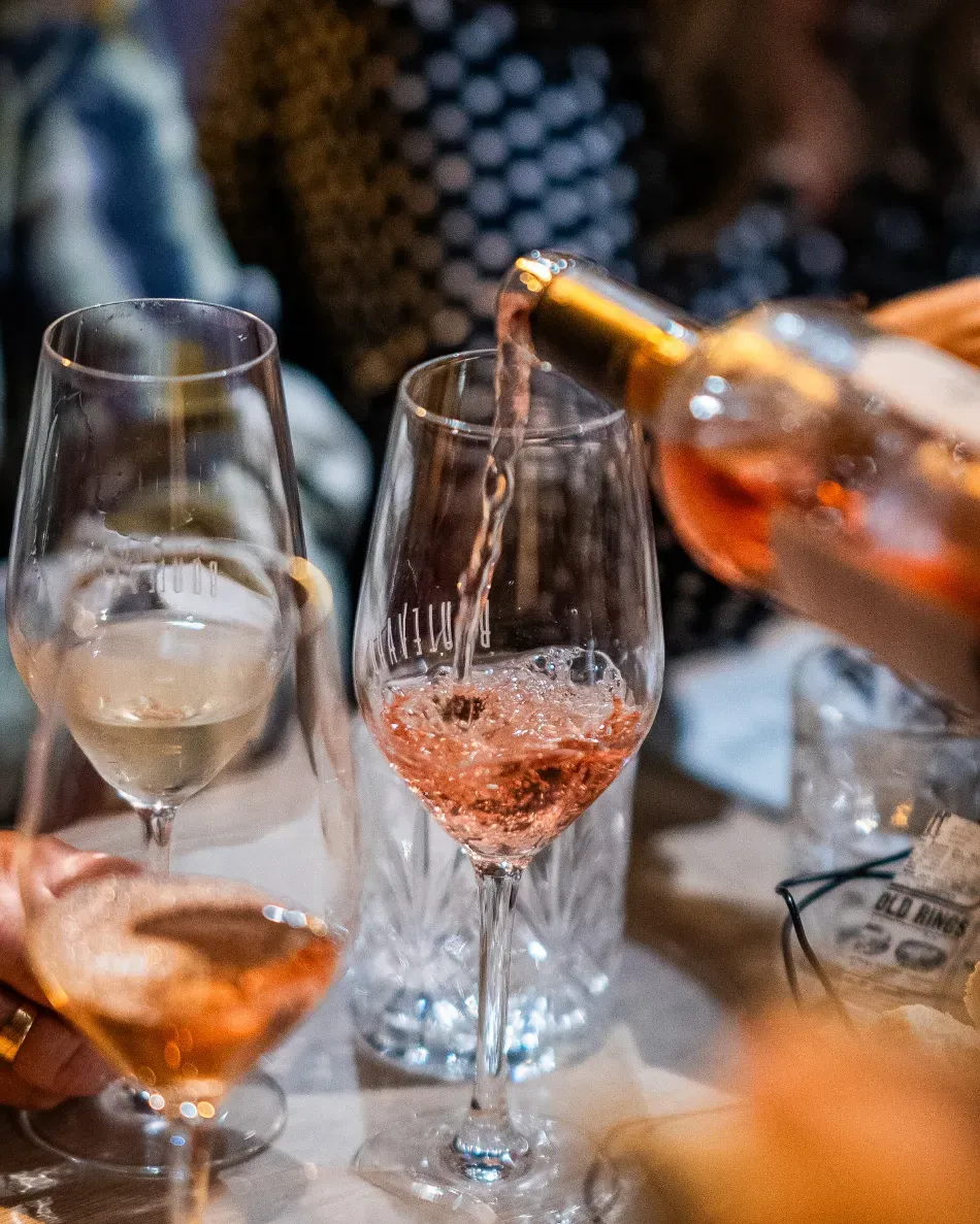 Se sirve vino en una copa en una reunión social, con otras copas sobre la mesa.