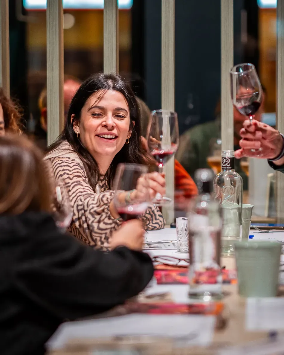 Amigos brindando con vino tinto en una cena a la luz de las velas en un restaurante acogedor.