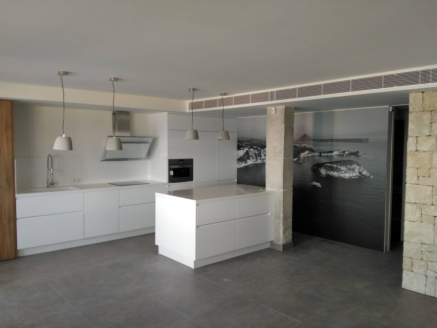 Una cocina con gabinetes blancos y una gran isla en el medio.