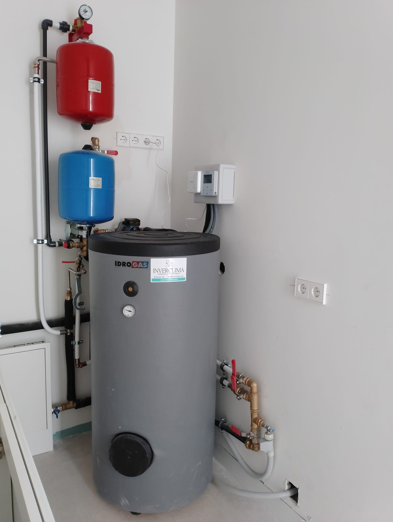 Un calentador de agua está ubicado en un rincón de una habitación, al lado de una pared.