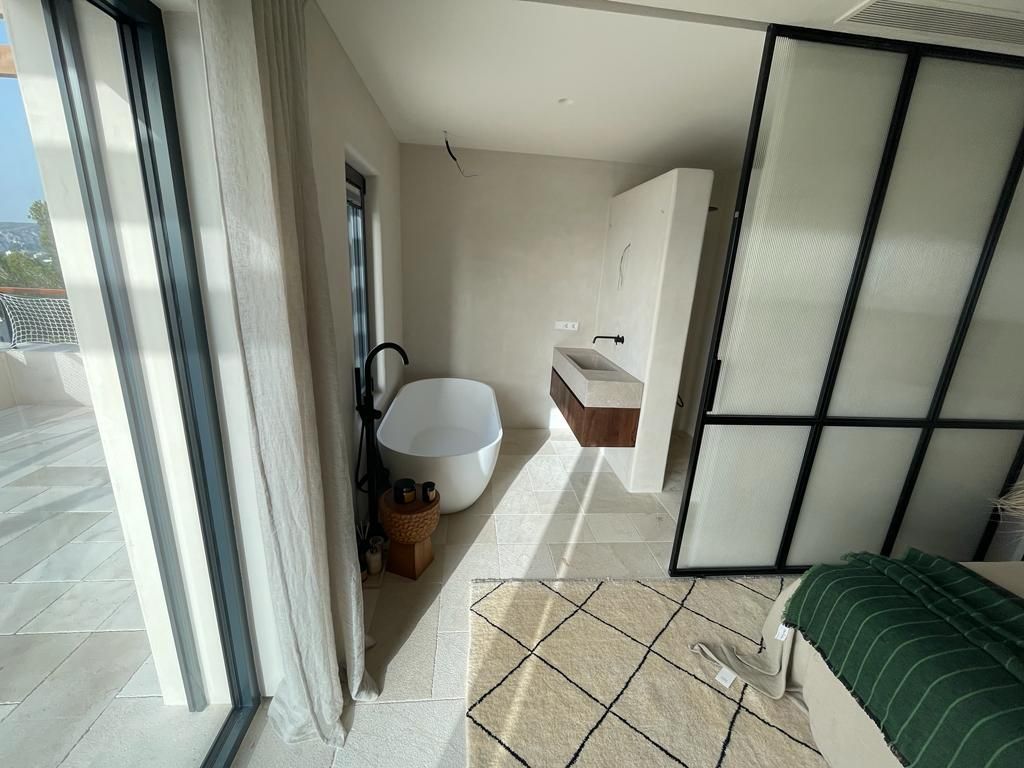 Un baño con bañera, lavabo y puertas corredizas de cristal.