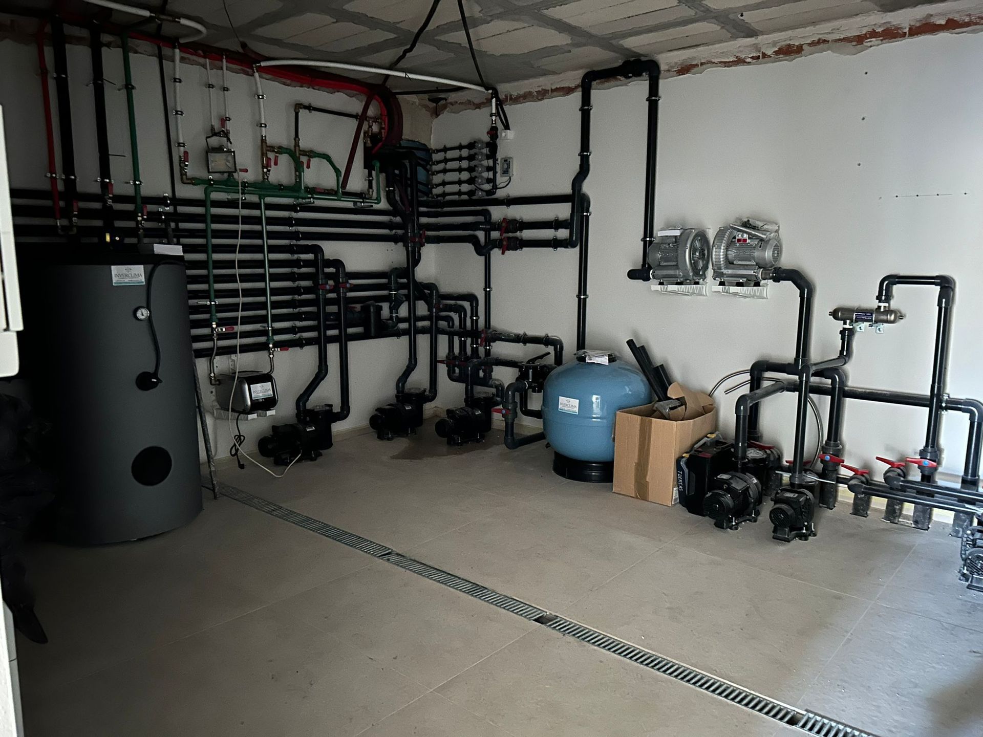 Una habitación con muchas tuberías y un tanque azul.