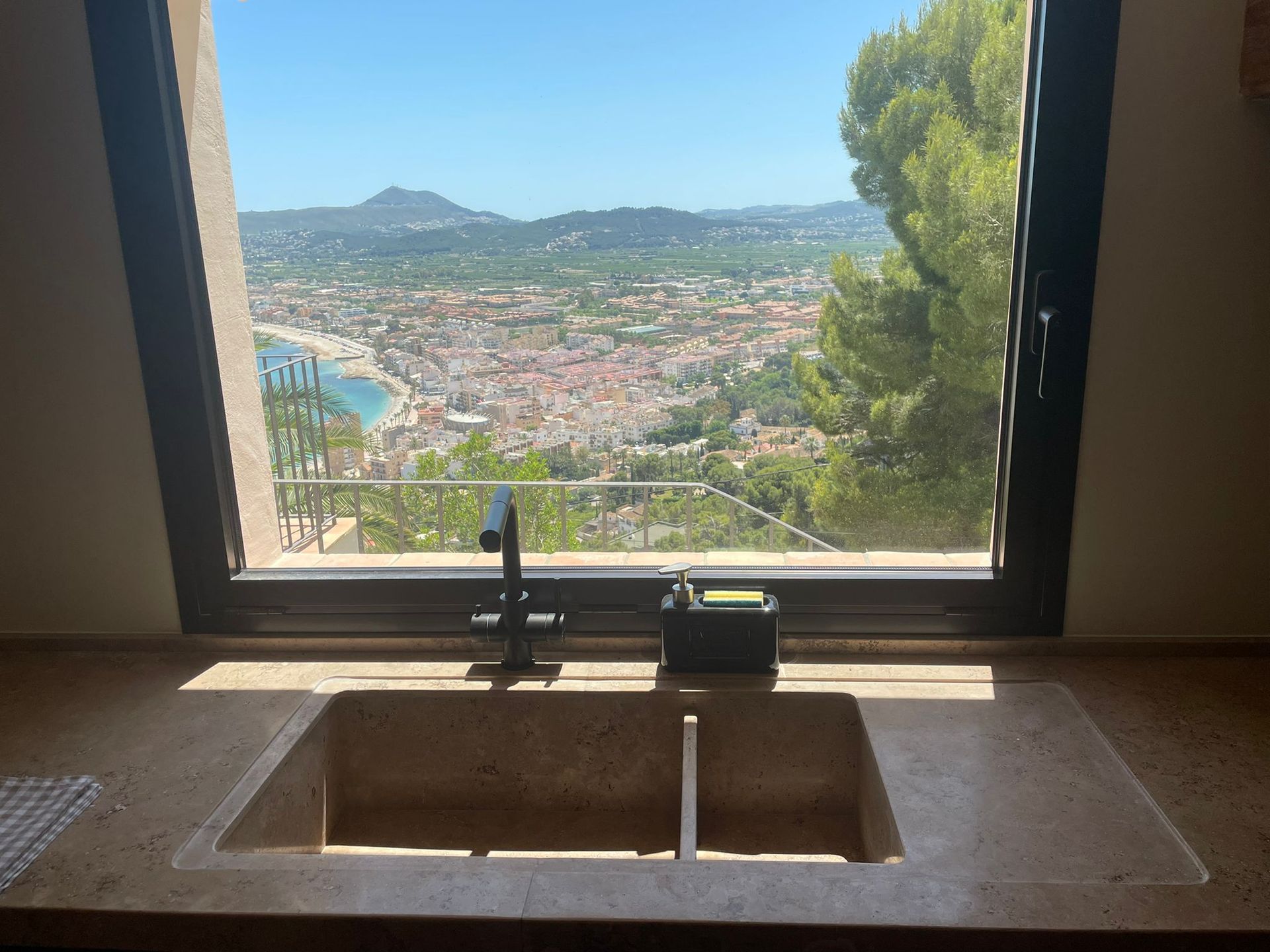 Un fregadero de cocina con vista a una ciudad a través de una ventana.